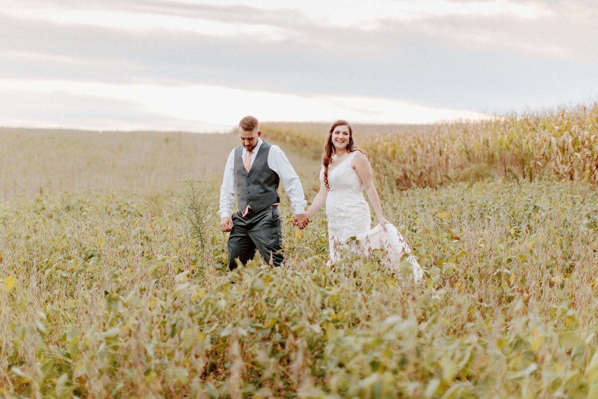Couple walking hand in hand through a n open field