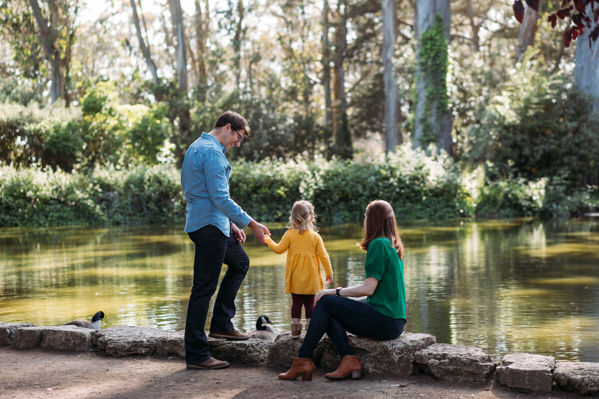 Family Photographer, a father holds his daughter's hand with mom nearby at a pond