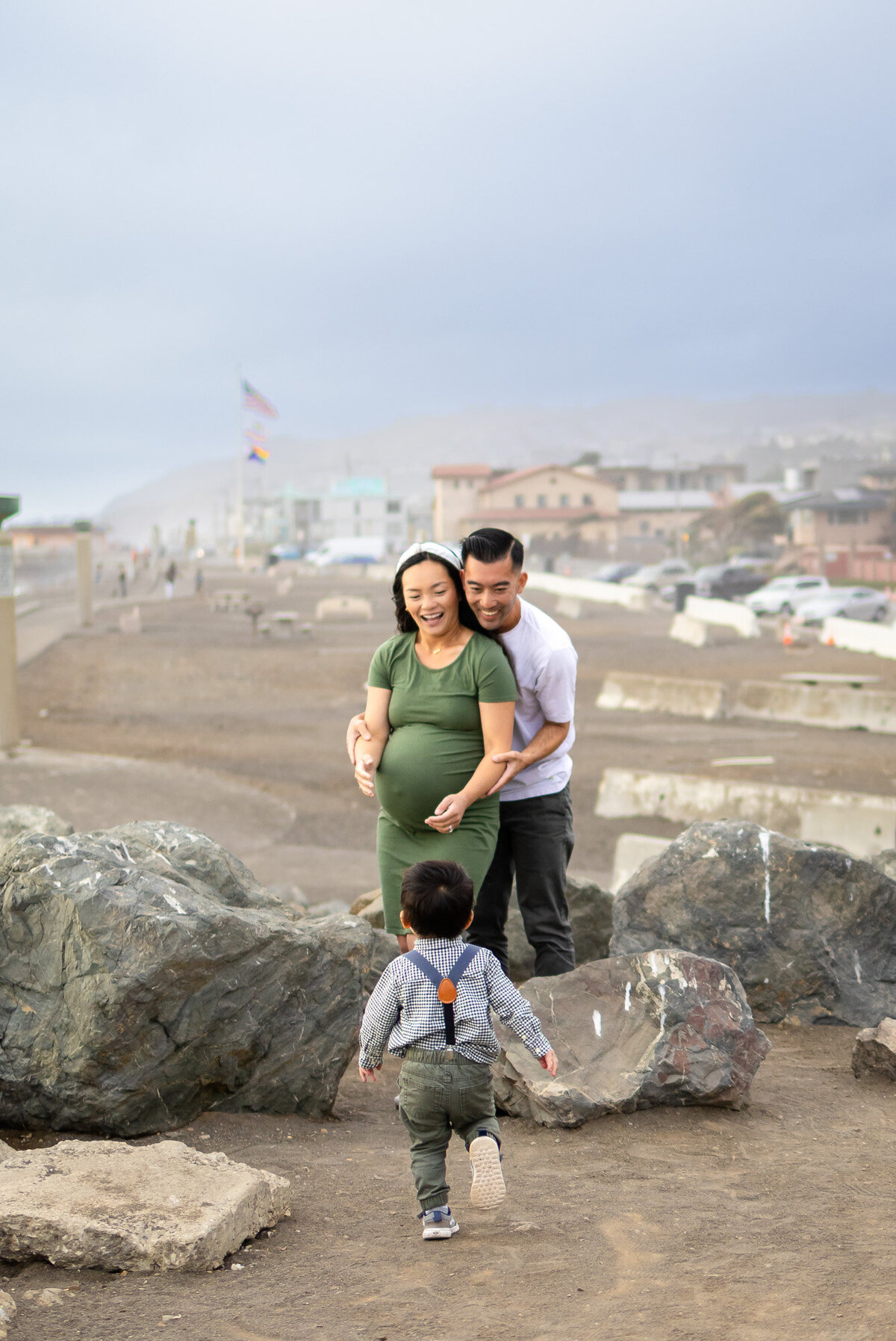 Candid photo of parents smiling at their toddler running toward them on the coastal trail, Bay Area Maternity Portfolio - Ellobelle Photography