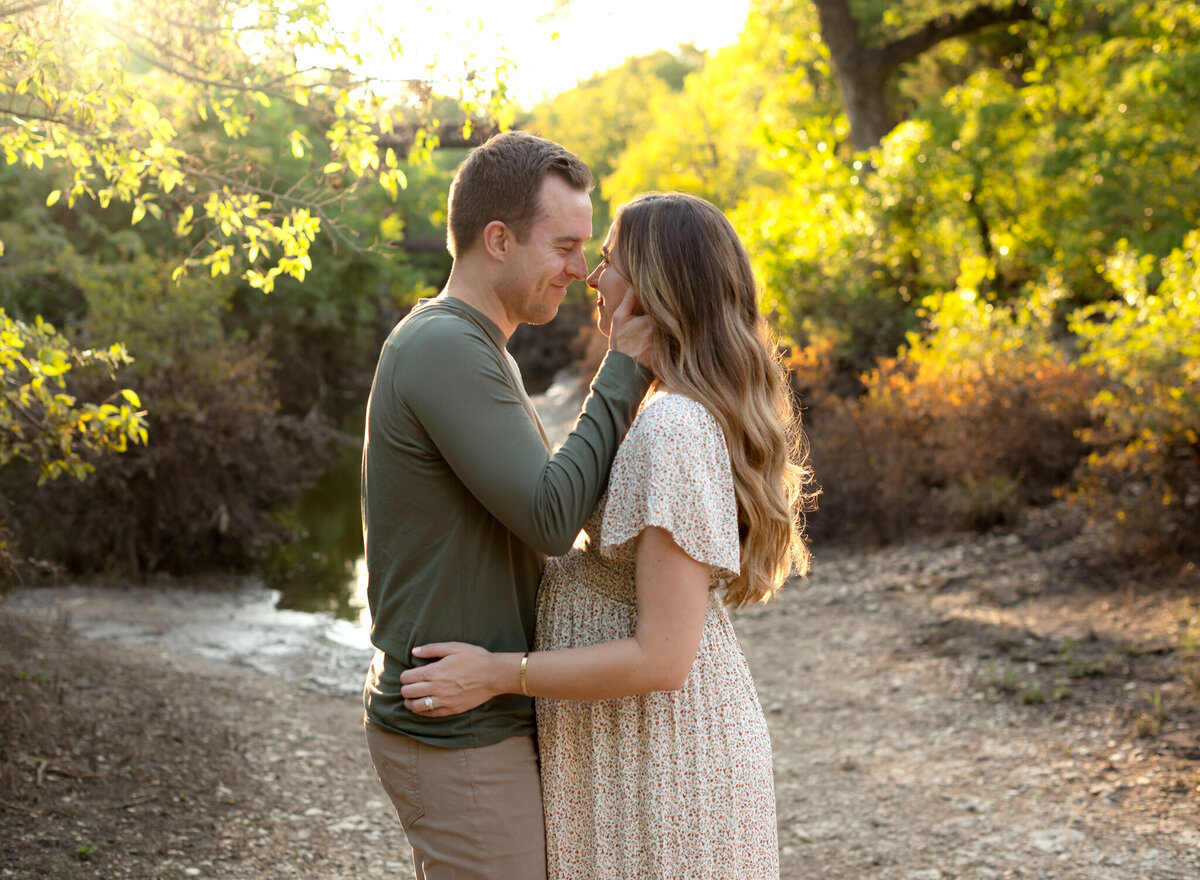 Couple smiles and embraces during golden hour maternity shoot near Westlake, Texas