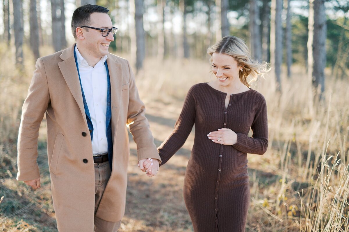 pregnant mom and husband running through the trees while smiling