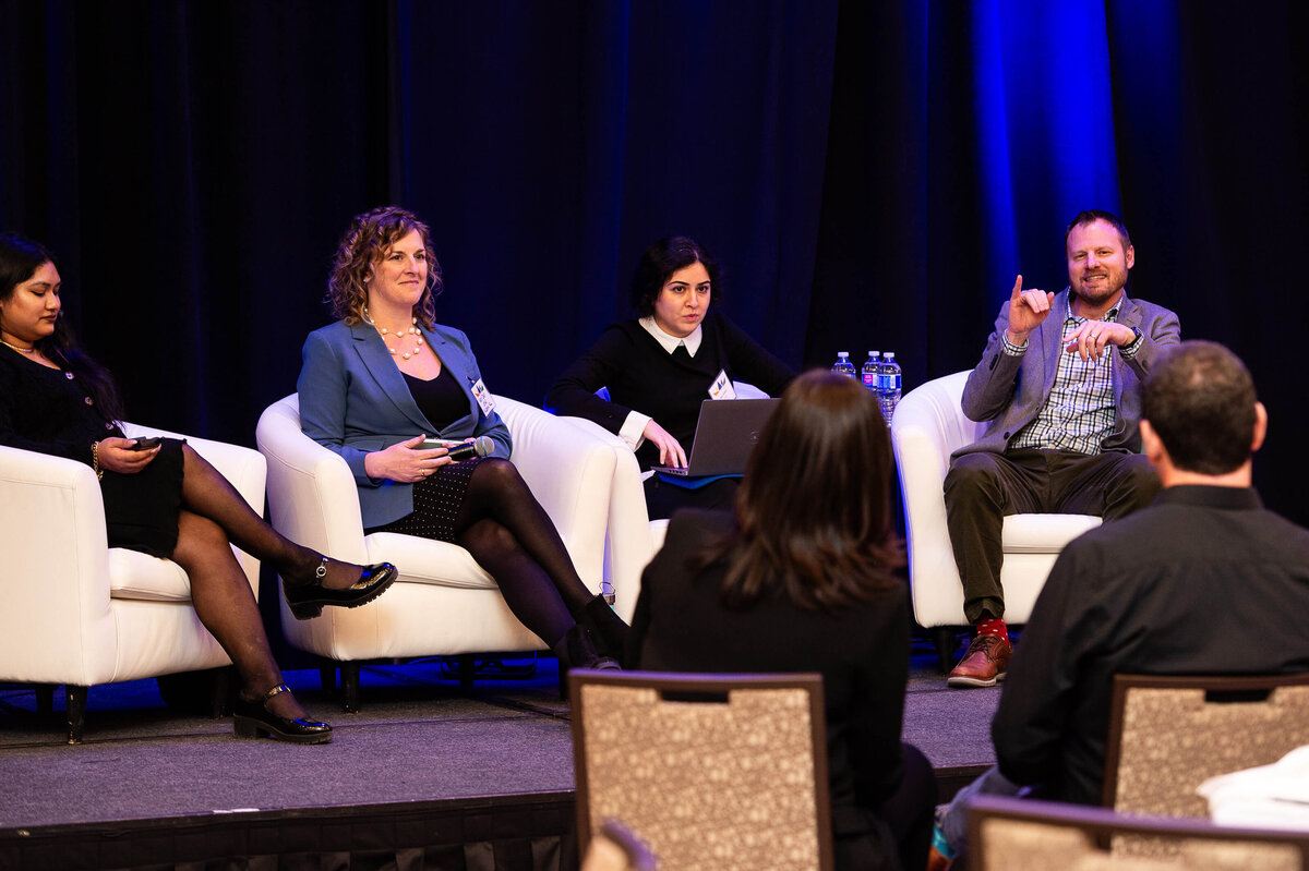 3 speakers on a stage speaking to the audience.  One man is signing.Captured by Ottawa Event Photographer JEMMAN Photography COMMERCIAL  