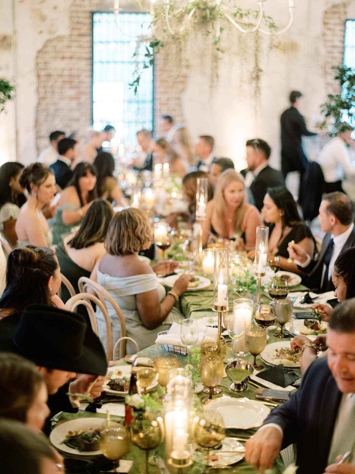 A vibrant reception scene featuring a diverse group of people, indulging in a delightful meal together, under dim lighting and surrounded by an elegant atmosphere, fostering connection.