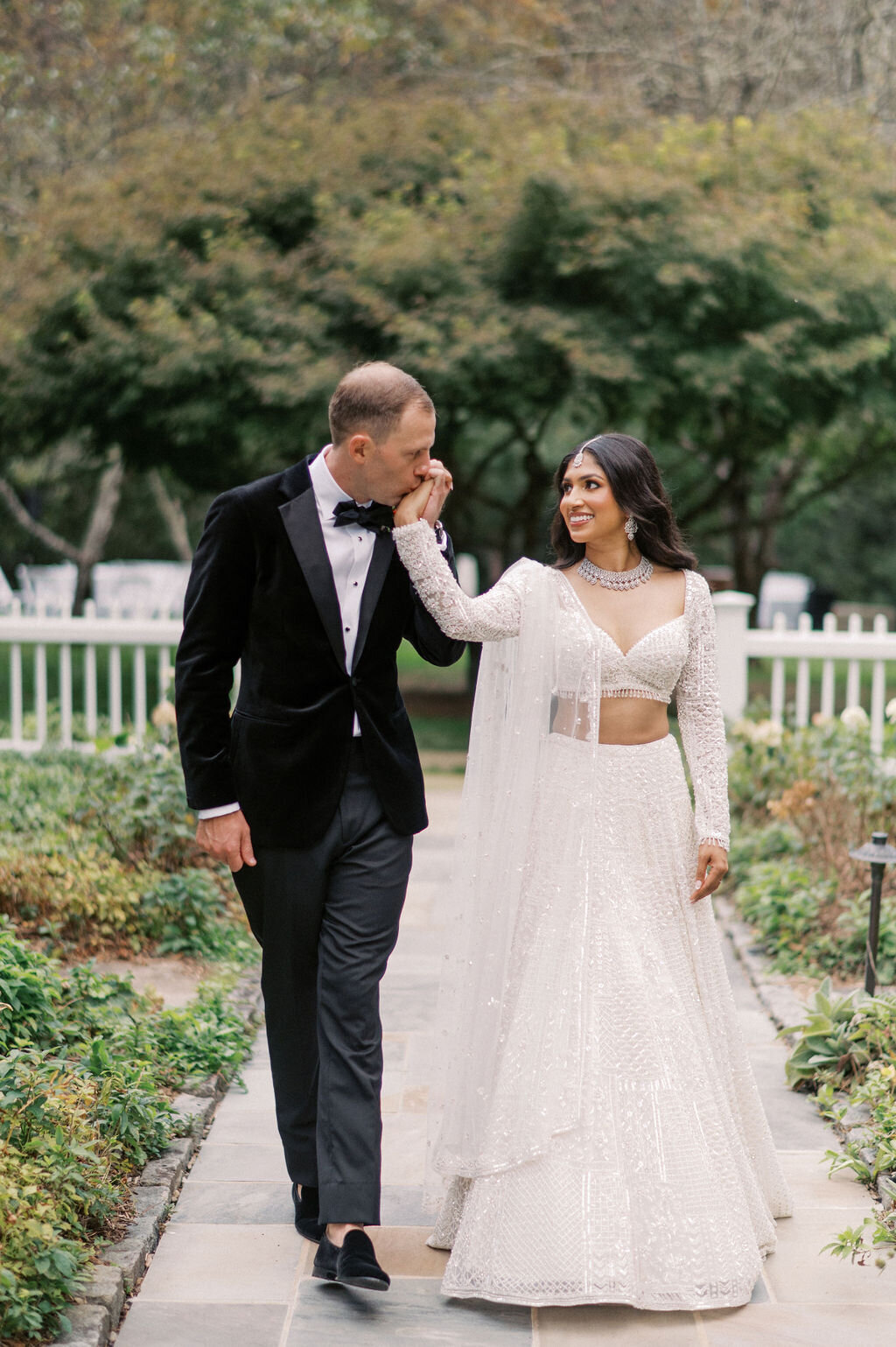 Groom kisses bride’s hand during a romantic garden moment at Old Edwards Inn in Highlands, North Carolina.