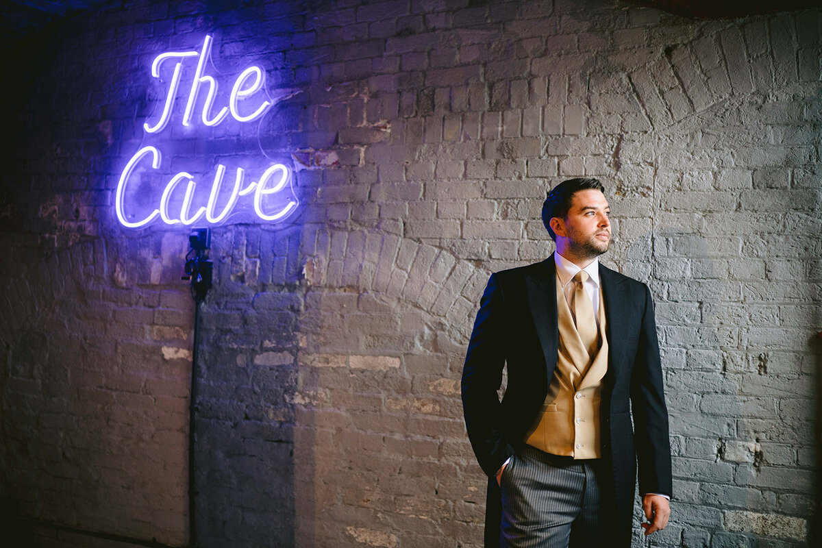 the groom in the man cave with the neon sign
