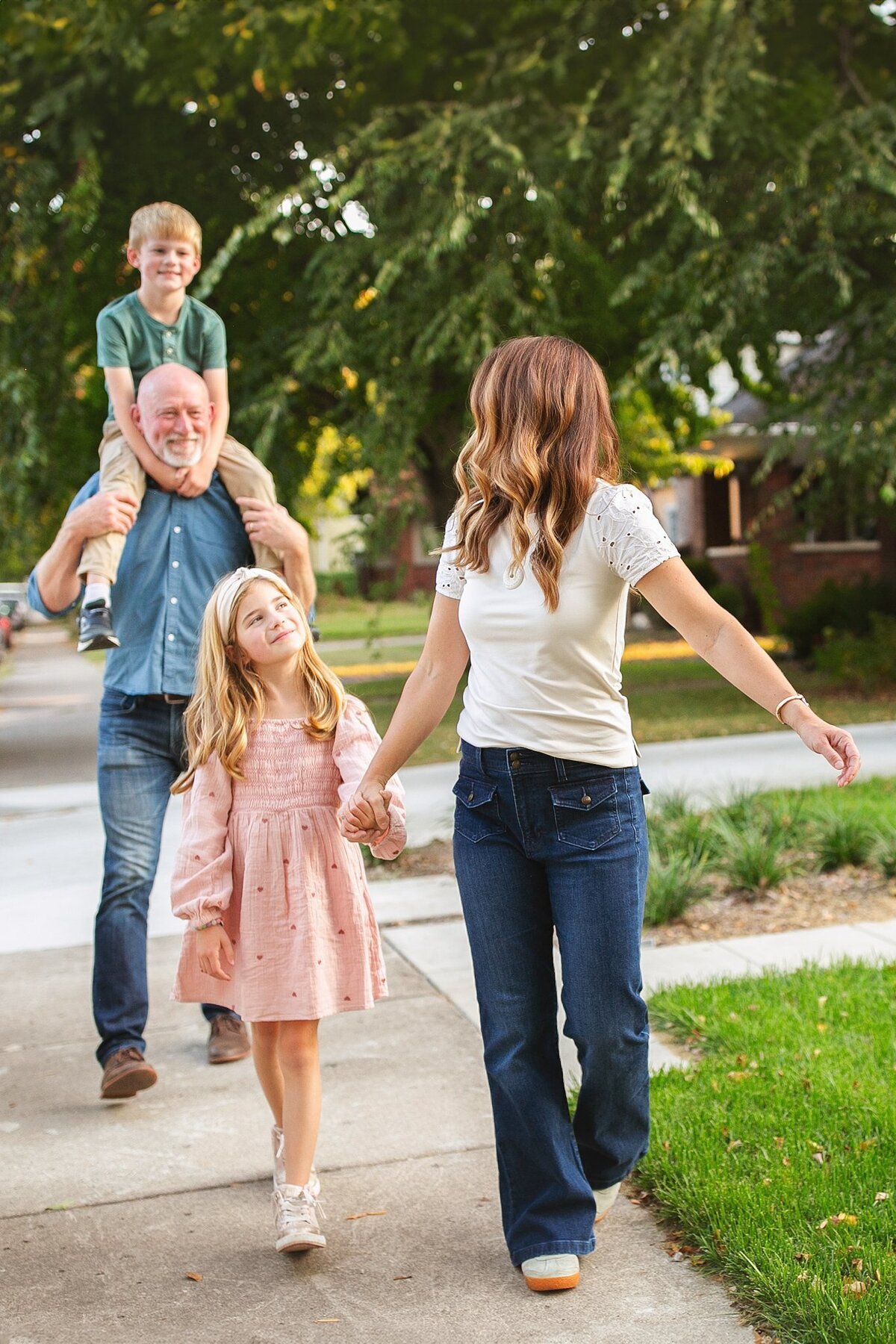 A-happy-family-walking-hand-in-hand-through-the-broad-ripple-neighborhood-in-indianapolis-near-the-colorful-flower-mural-during-a-sunset-photo-session