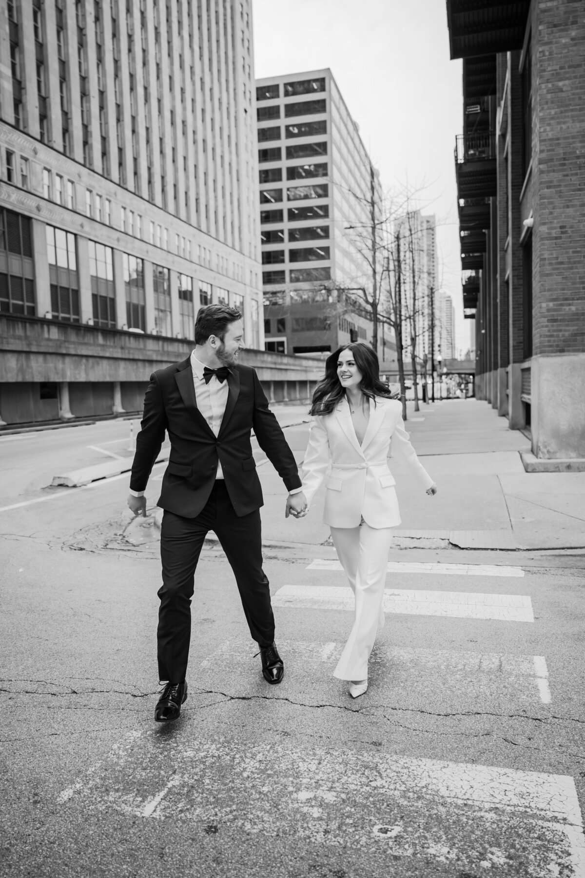 A couple holds hands while running a cross the street.