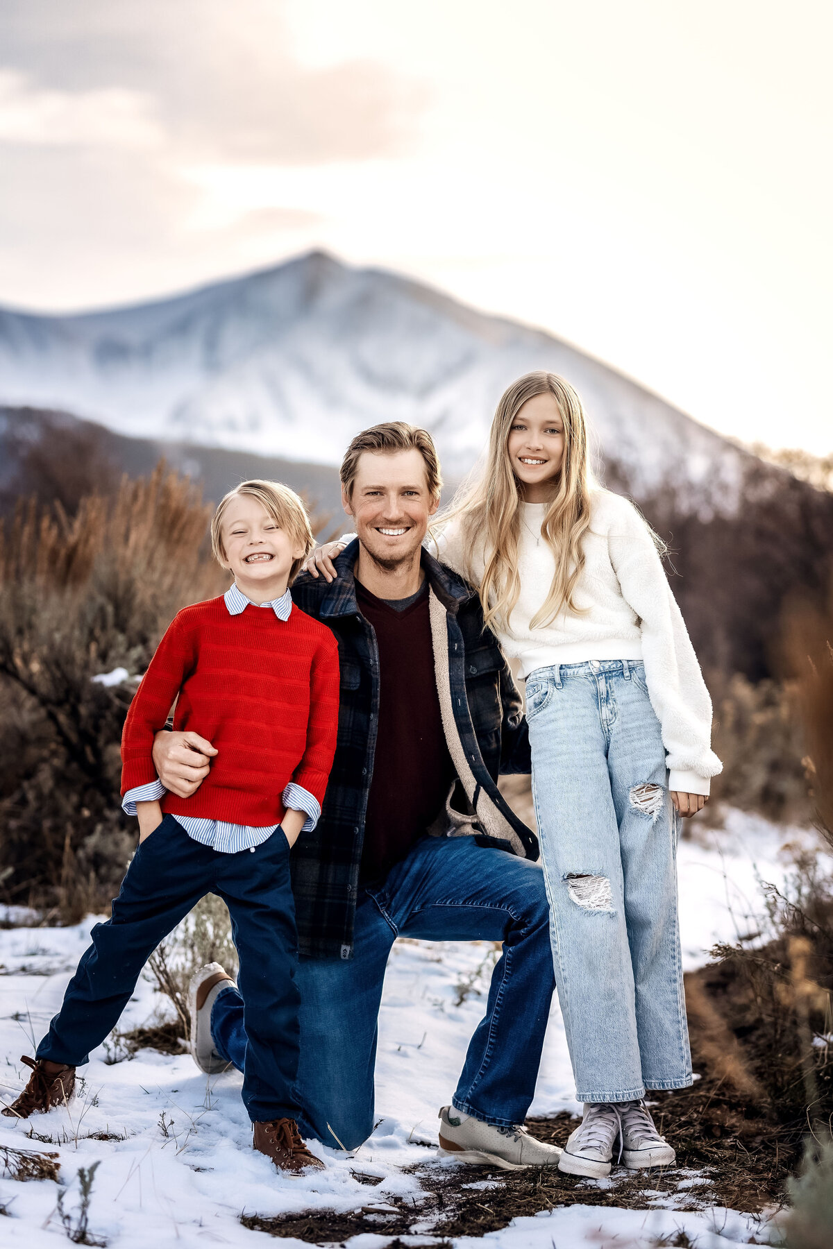 A cute dad and his two children, posing for a photo.