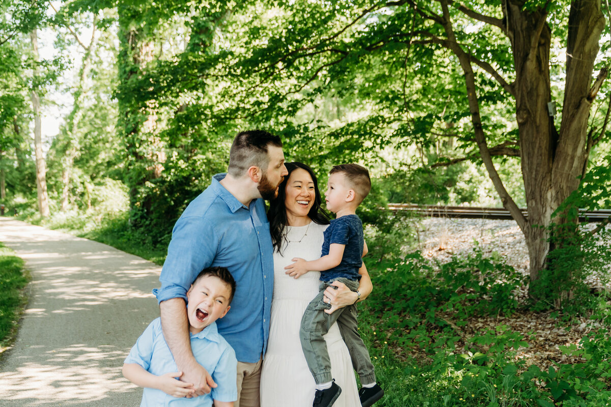 A family laughing together during an outdoor family documentary session in Bath, Ohio, captured in a candid, documentary style.
