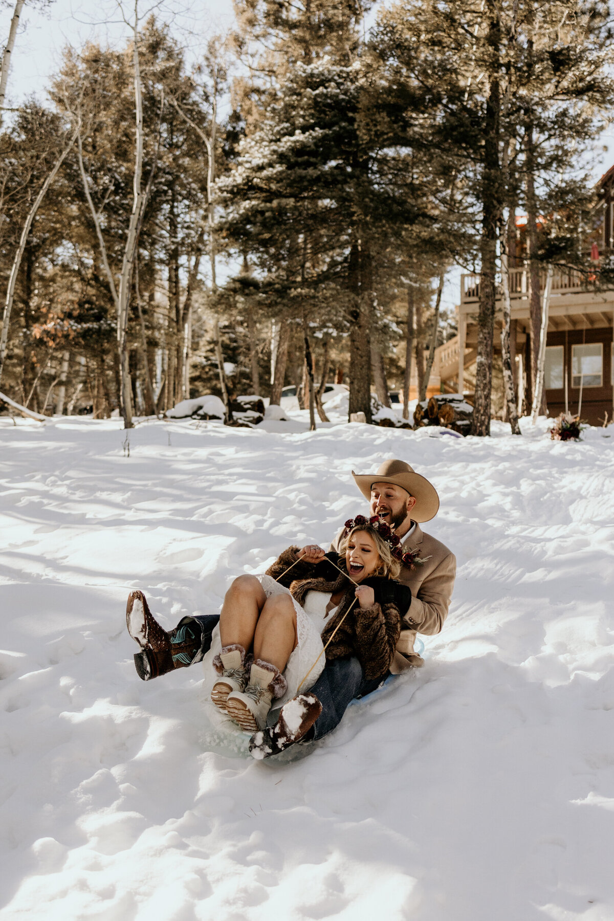 Bride and groom sledding on a hill in Angel Fire, New Mexico