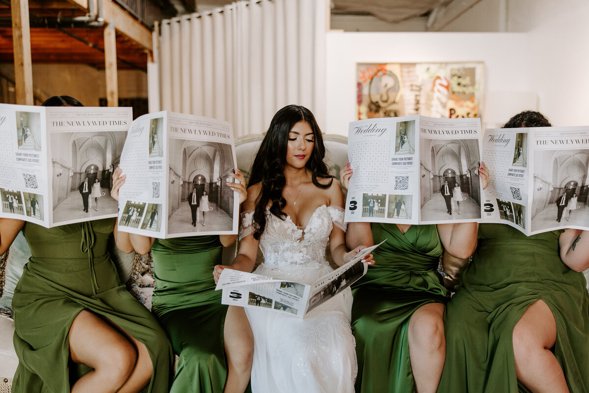 A bride reads a newspaper while her wedding party also holds up newspapers to cover their faces.