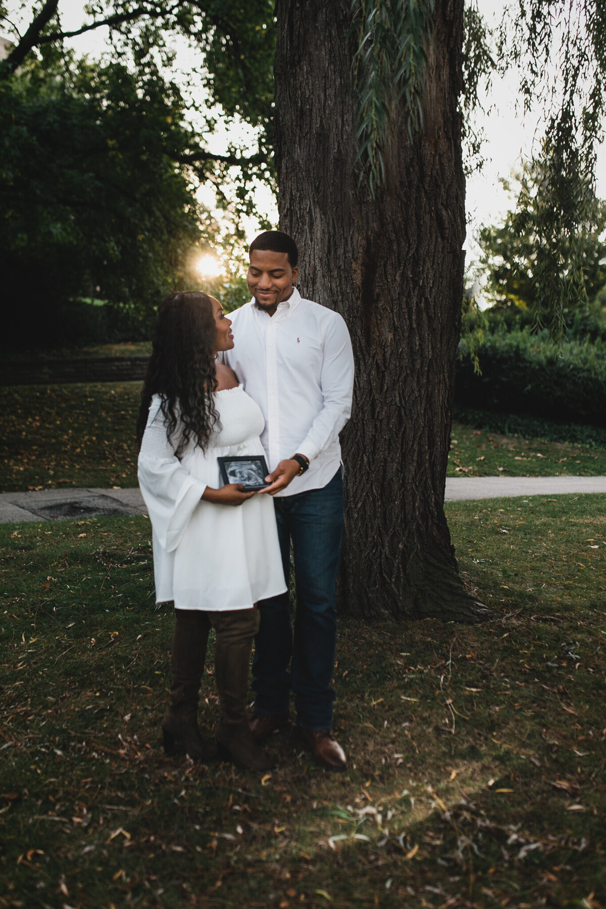 Pregnancy photograph of woman and man holding ultrasound picture.