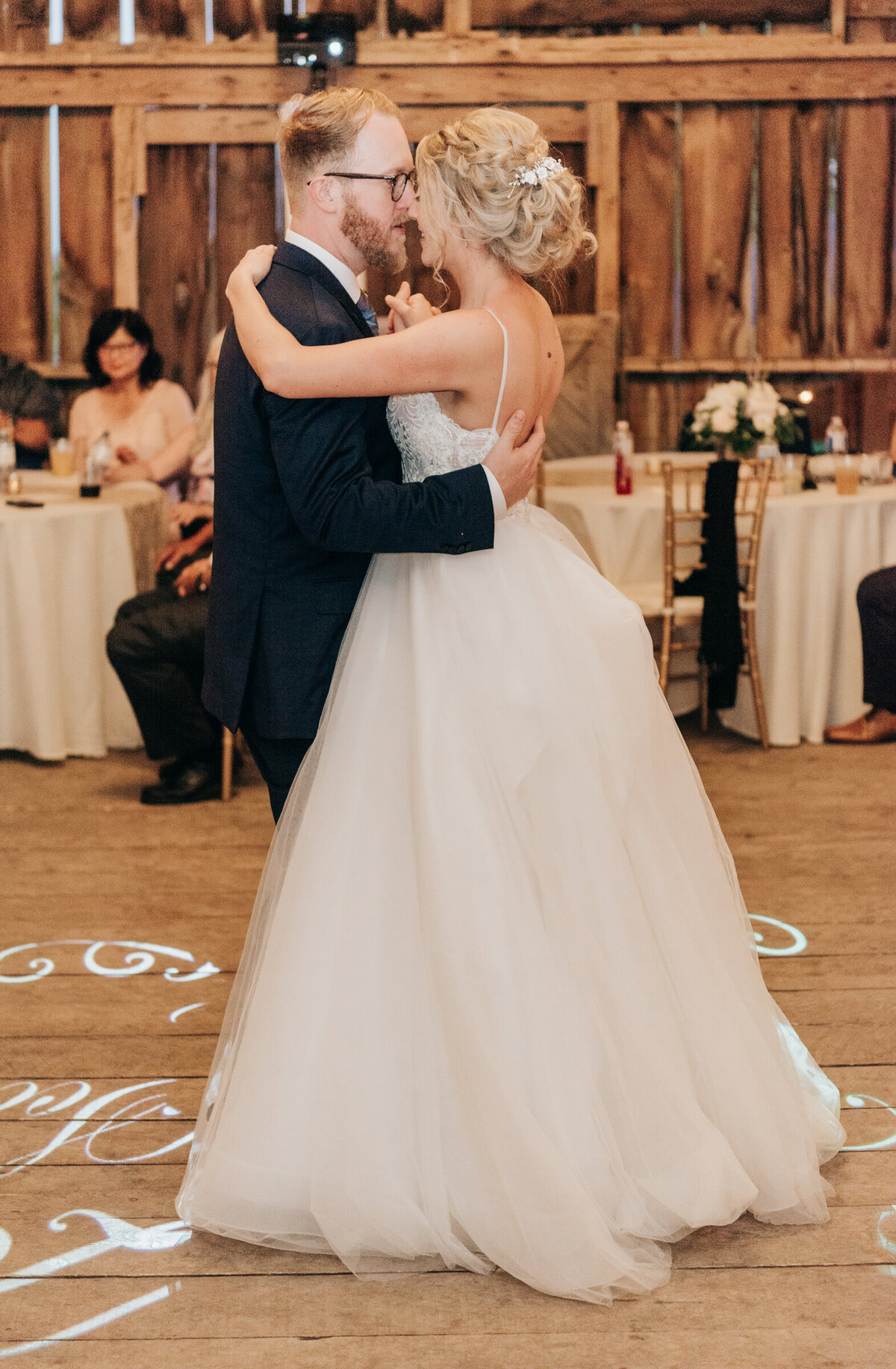 Bride and groom enjoying their first dance at glamorous Willow Creek Barn reception photographed by Nova Markina