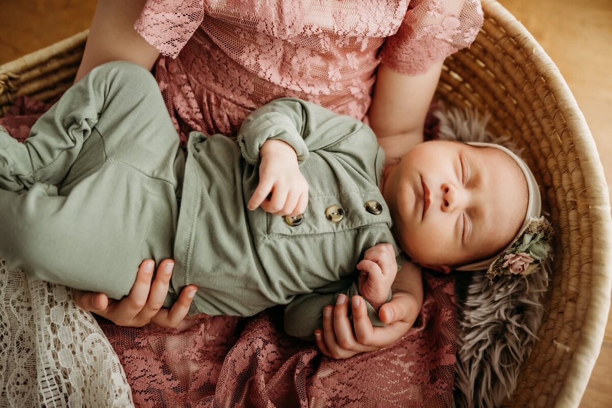 overhead photo of newborn baby sleeping in big sisters arms