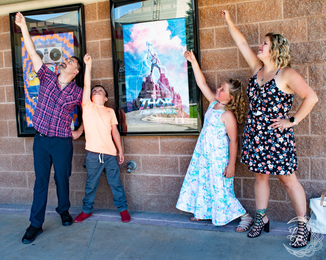 Family photo of 4 posing in front of a movie poster