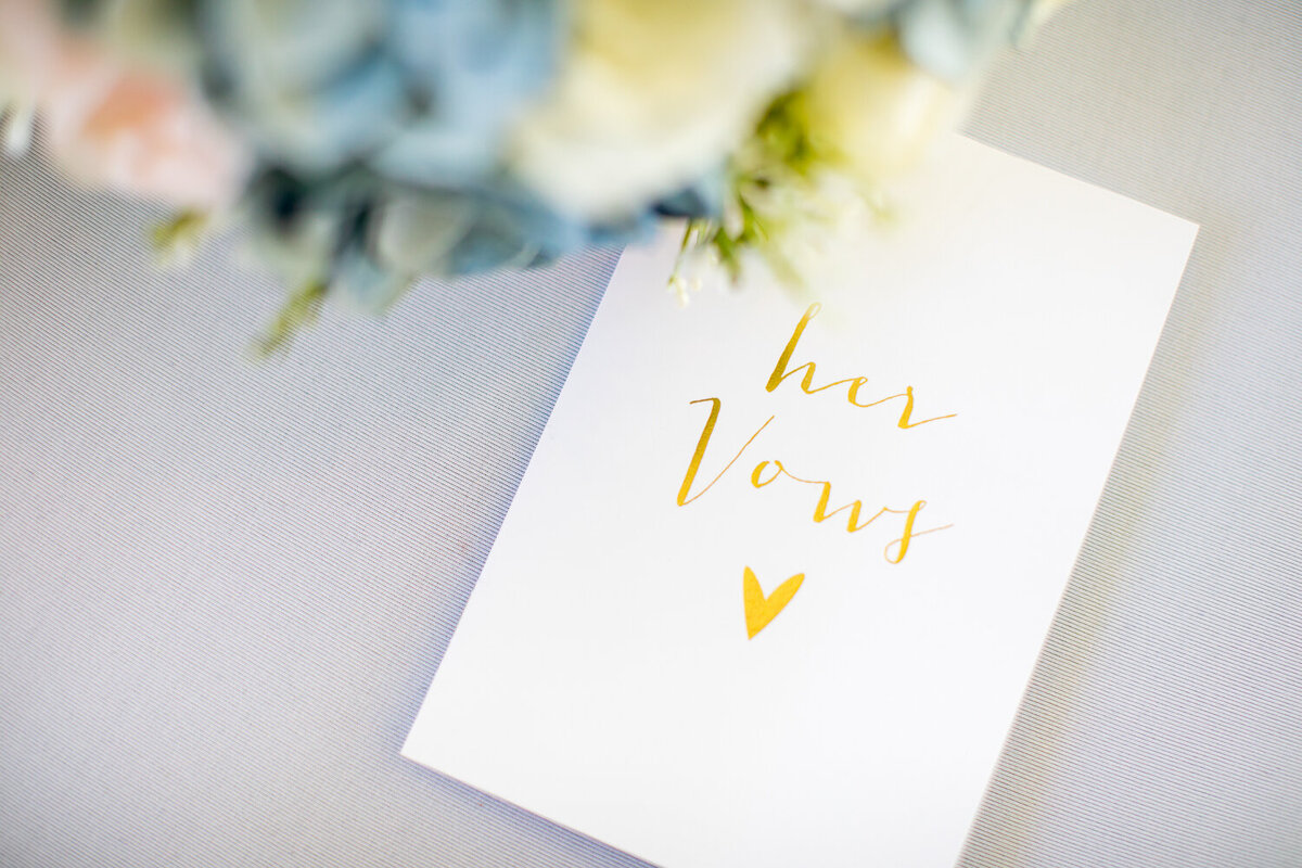 The bride displays her wedding  vows in a white booklet with gold lettering