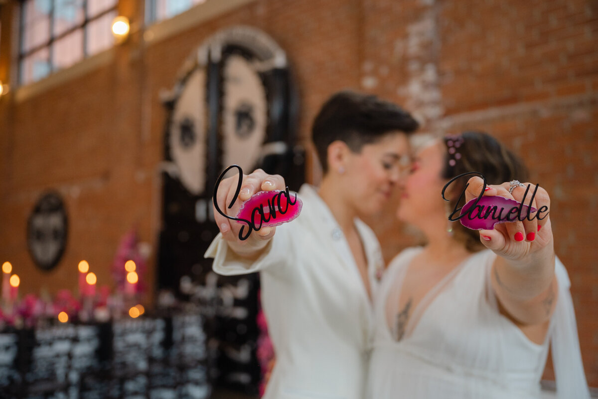 Brides holding their table names "Sara" and "Danielle"