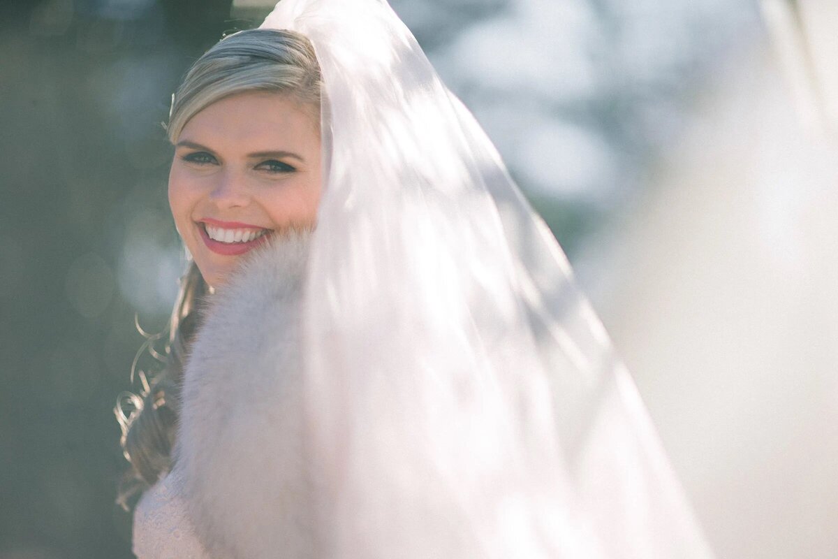 A bride smiling and looking back across her body