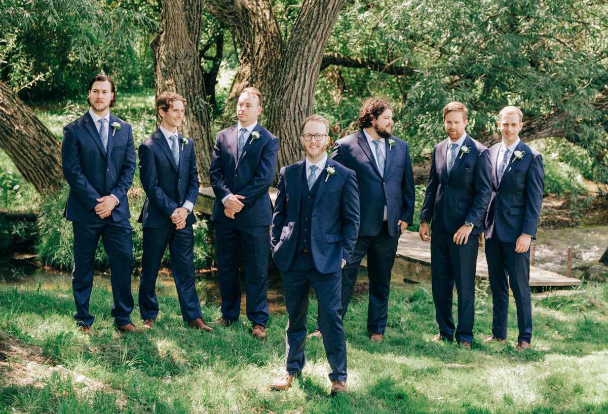 Groom and groomsmen wearing navy suits during outdoor wedding portraits