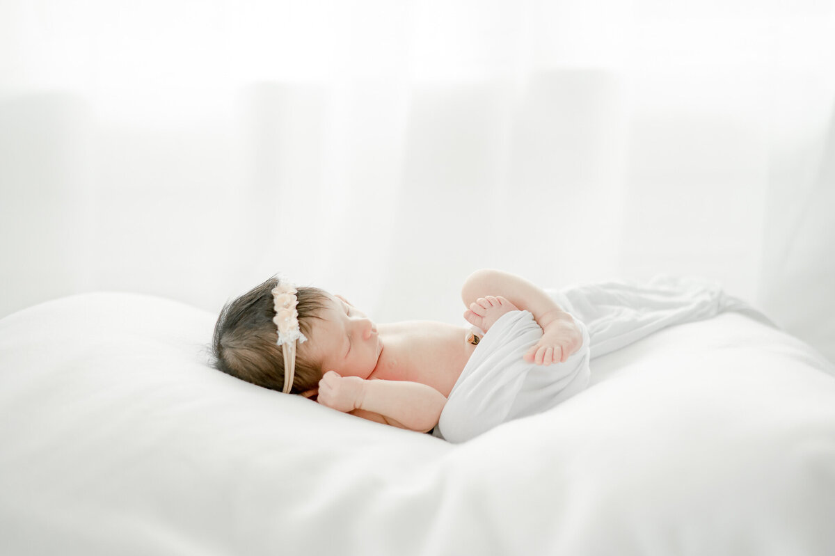 newborn sleeps on a white bean bag In Kristie Lloyd’s Nashville newborn photographer studio
