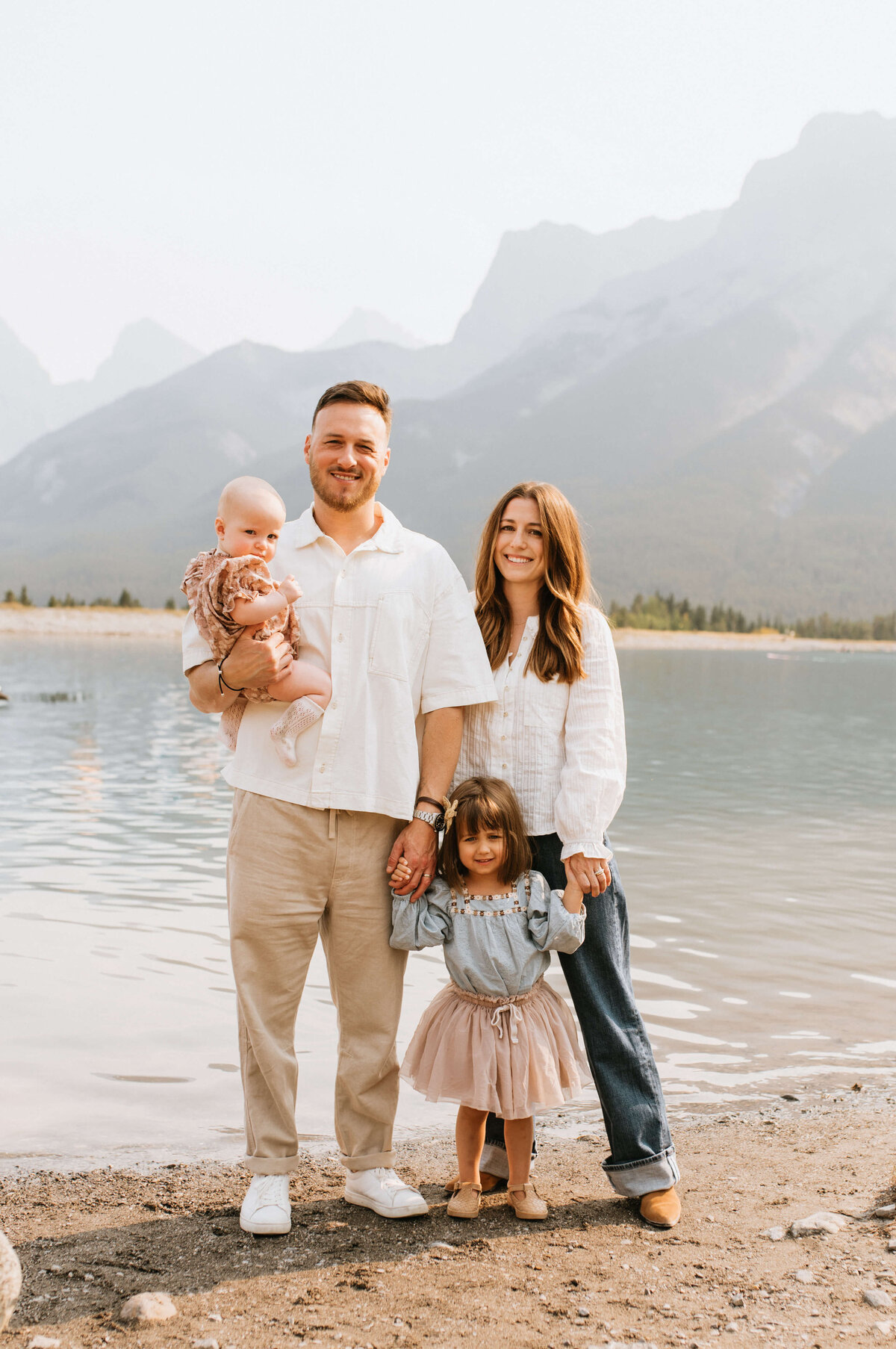 Beautiful-family-standing-infront-of-water-and-mountains-in-Canmore-Alberta-Canada