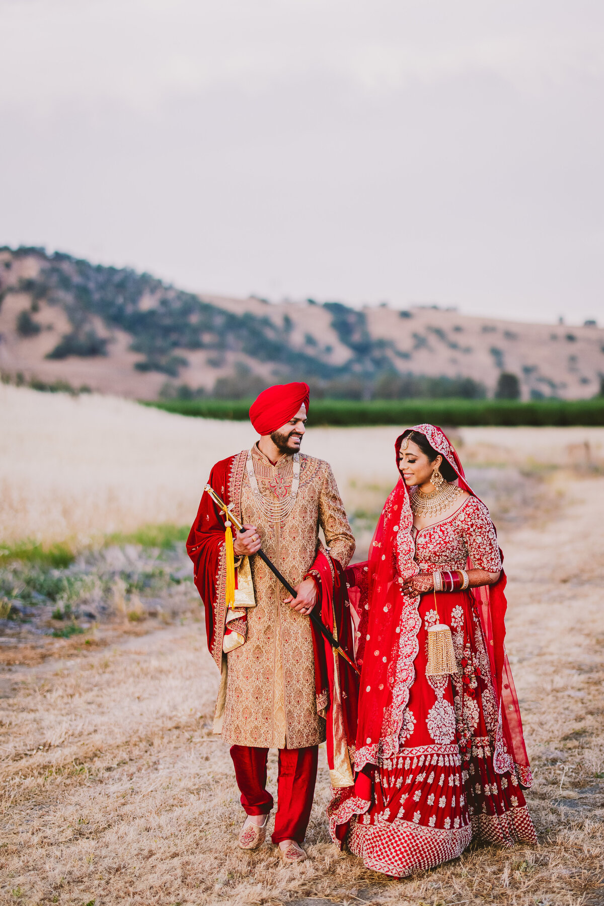 A sikh bride and groom walking on a dirt road in yuba city california on their wedding day