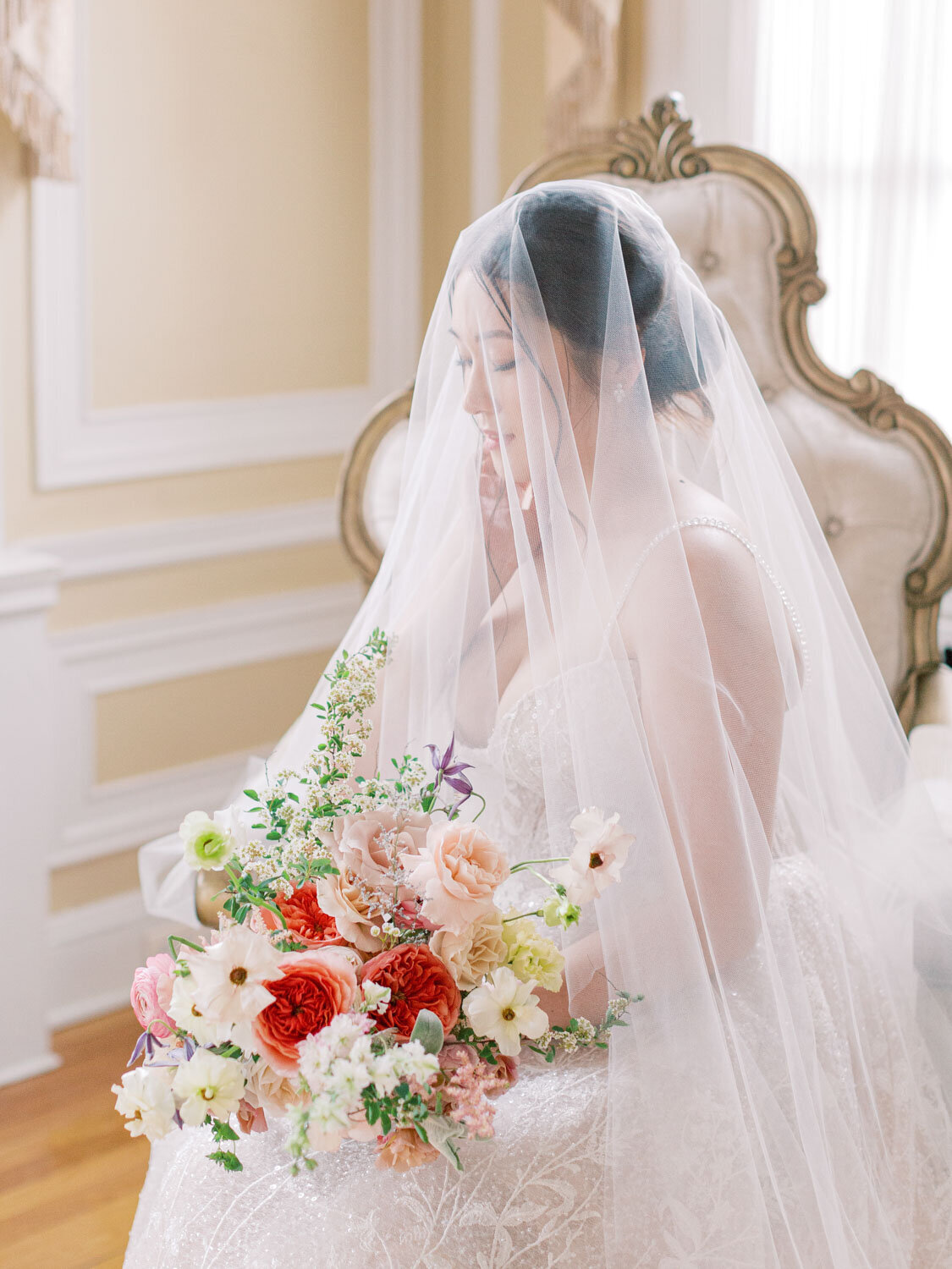 Bride sits with bouquet under her veil