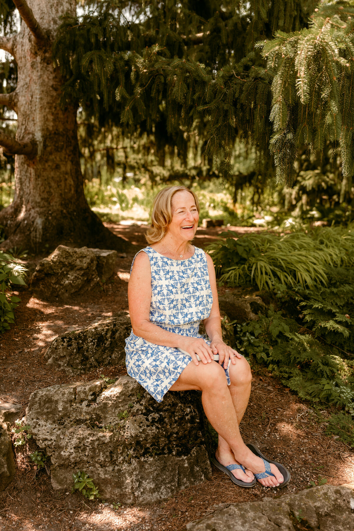 Outdoor dating profile photo of Linda in Minnesota, sitting under a large tree in a sunlit park.