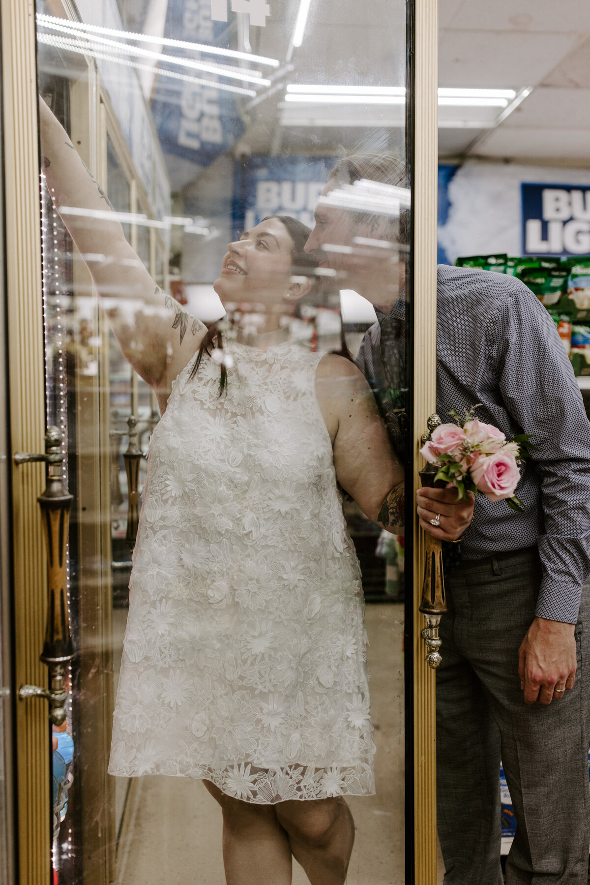 A couple leans in to grab a drink at a convenience shop.