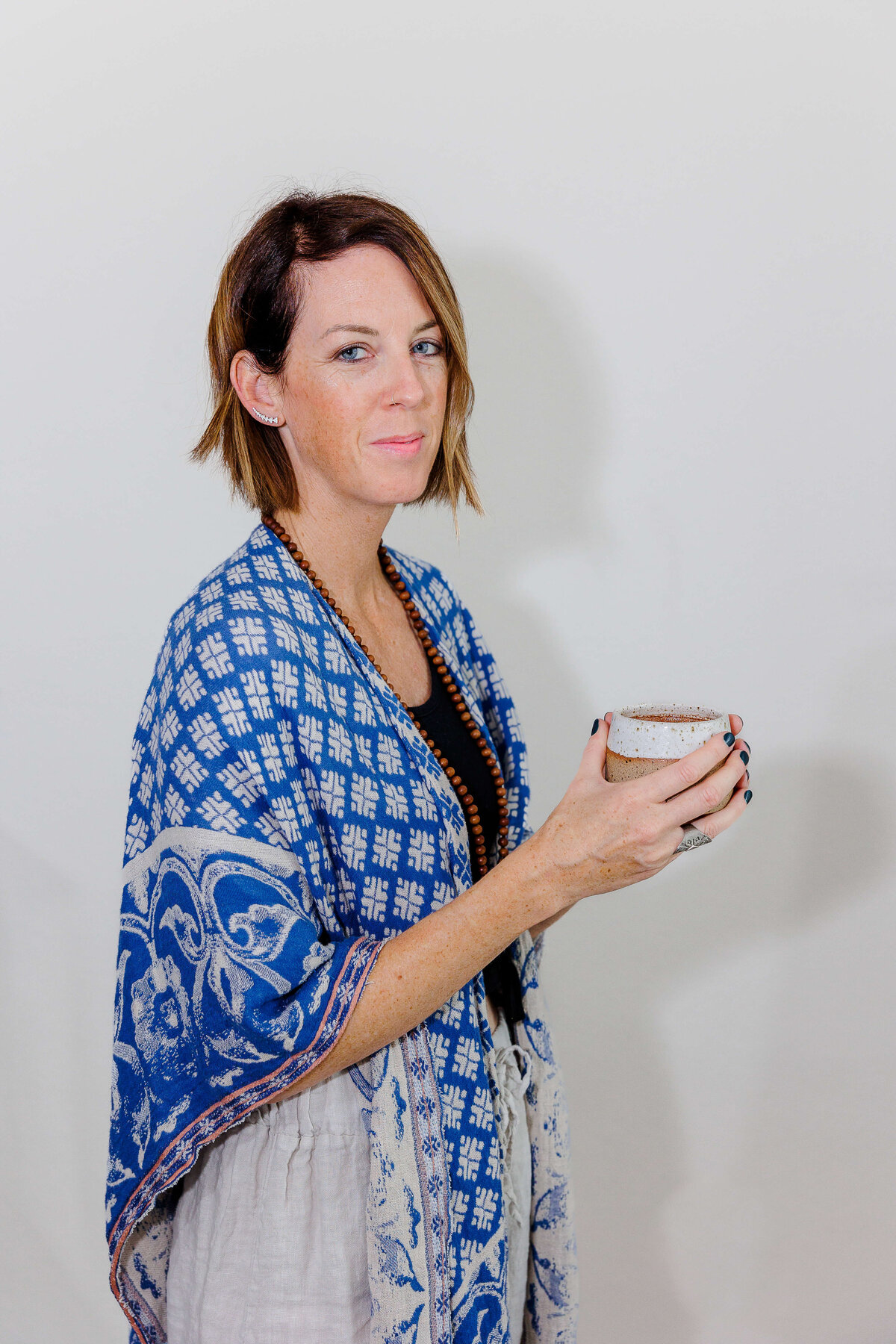 Lady in blue wrap holding hot chocolate at her branding session