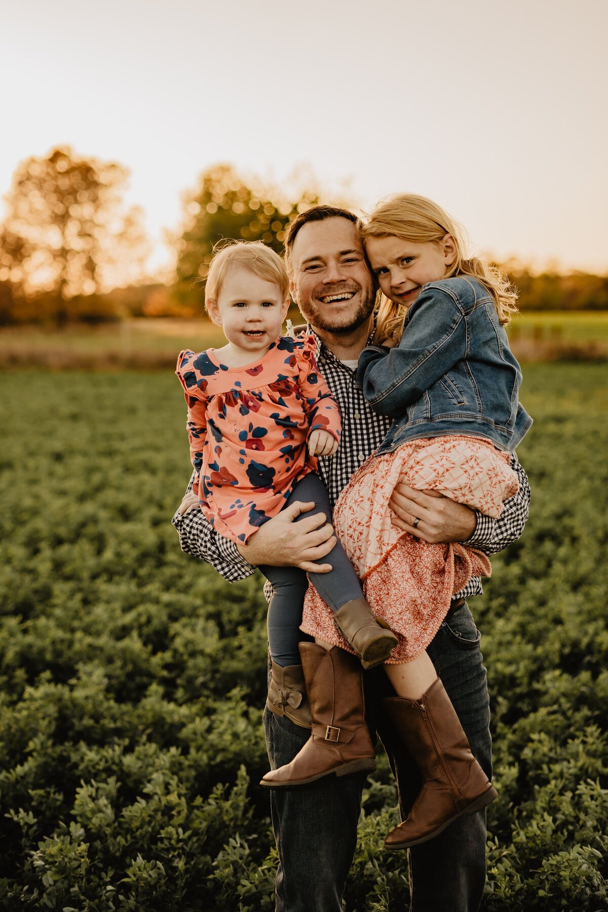 storyteller-collective-photo-co-dad-holding-daughters-in-sunset-field-iowa