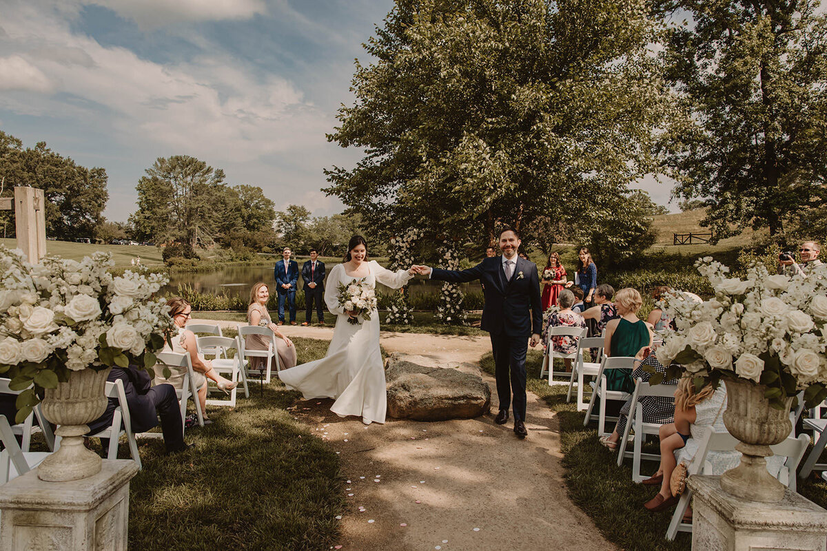 Newlyweds holding hands as they walk back up the aisle 