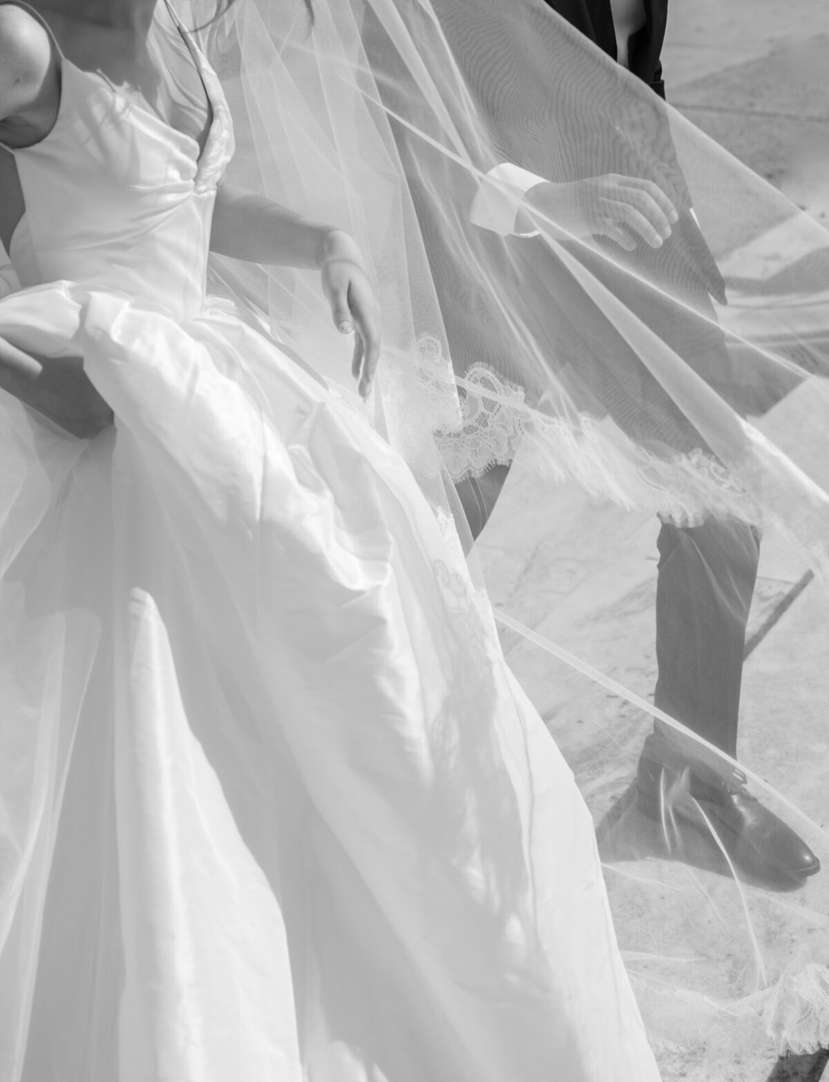 candid wedding photography in Detroit shows a bride and groom's hands among a long lace cathedral veil