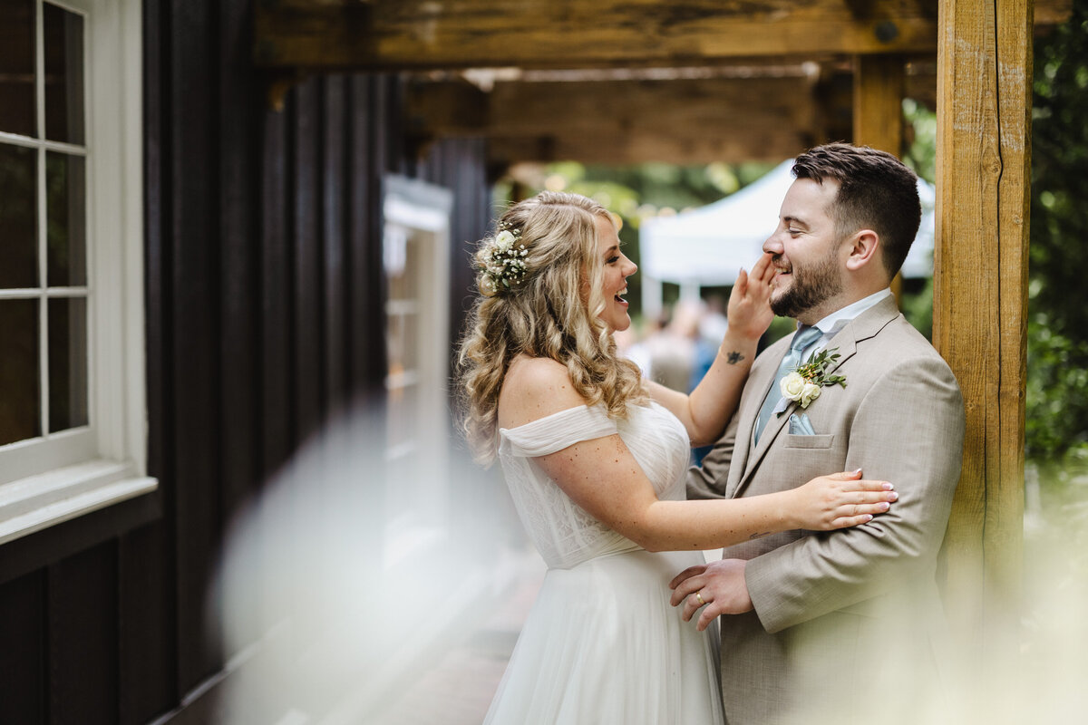 A wedding couple reaching out towards each other and laughing
