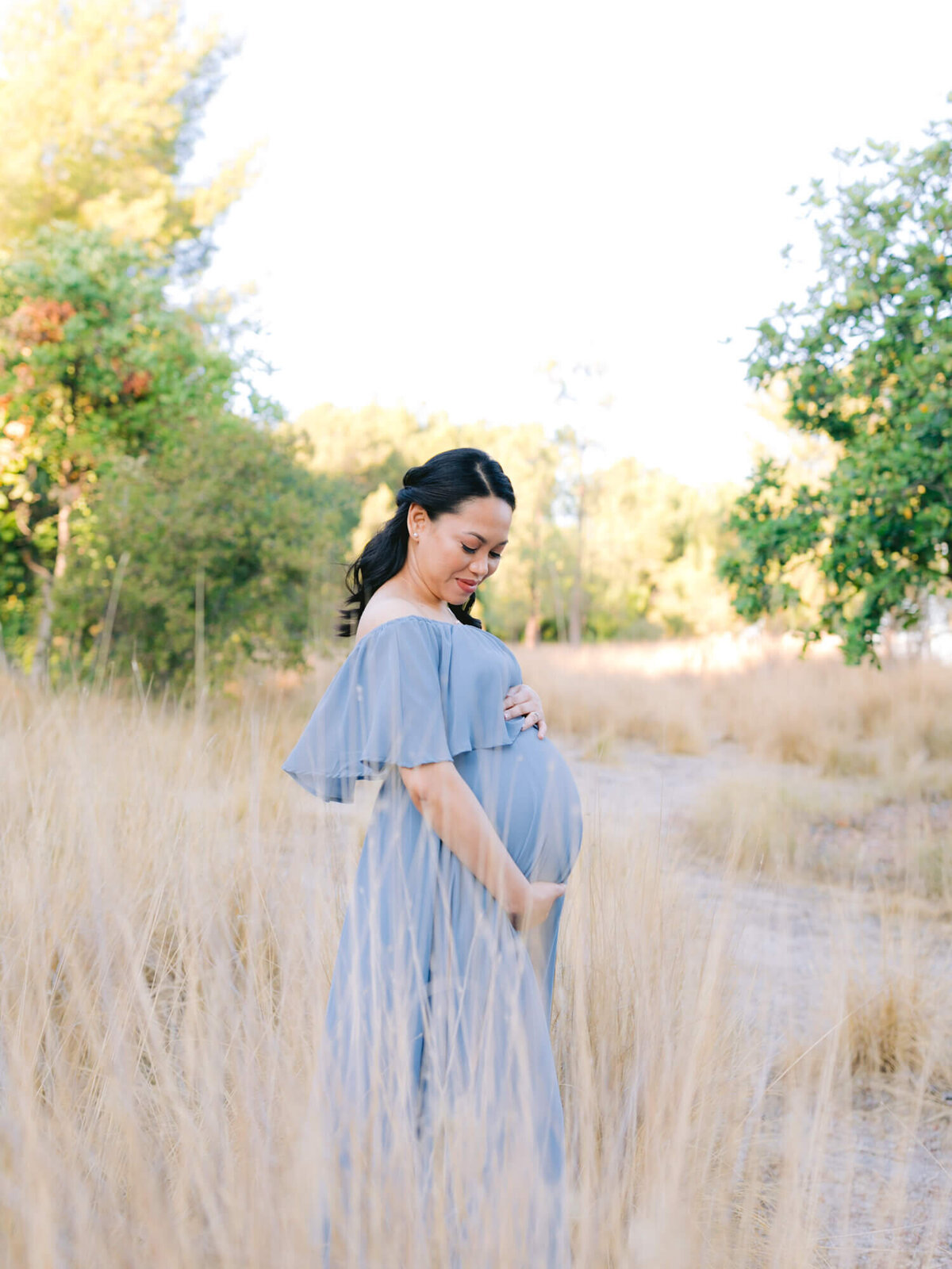mom looking down at pregnant belly maternity photoshoot