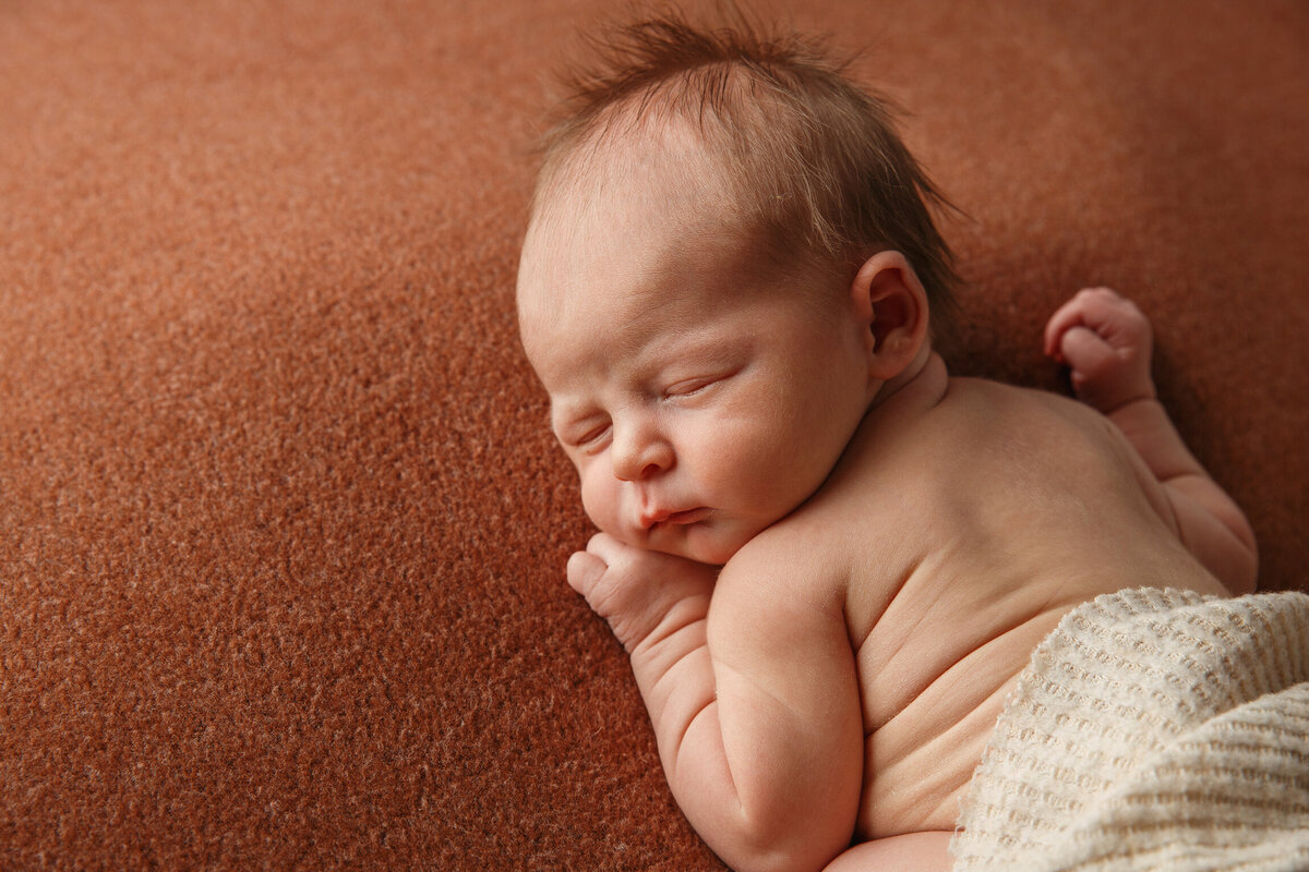 Portrait of a sleeping baby laying on a brown blanket photographed by Life in Pink Photography