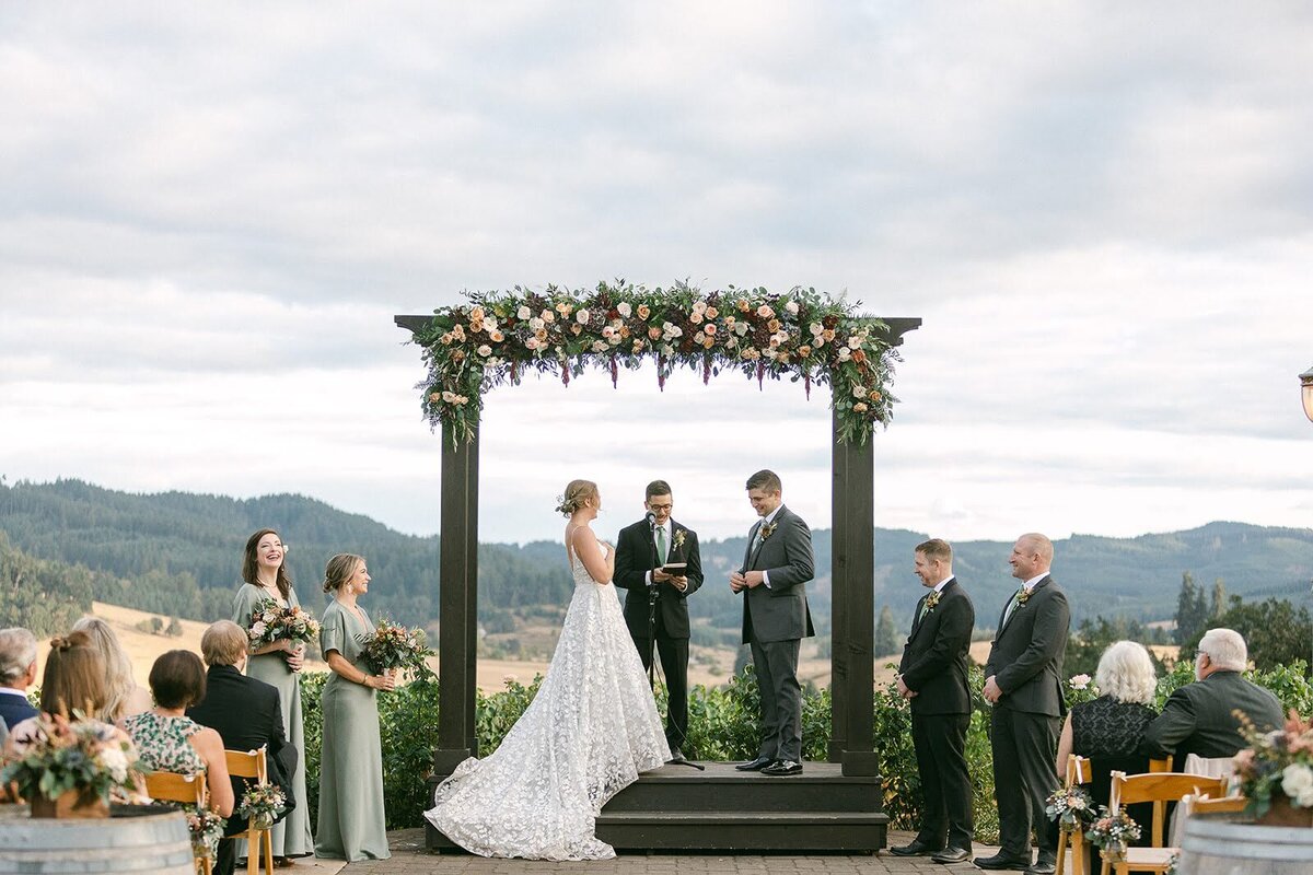 Wedding ceremony under an arch with beautiful floral installation across the top.