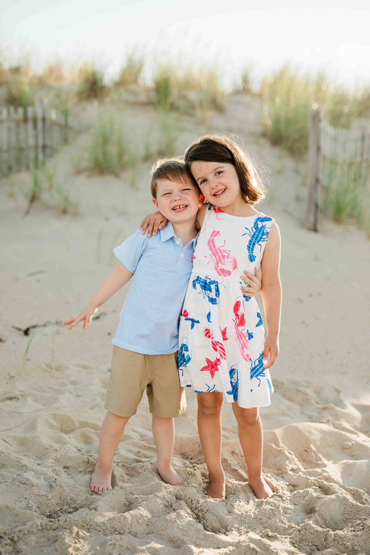 Brother and sister standing on beach with sunset