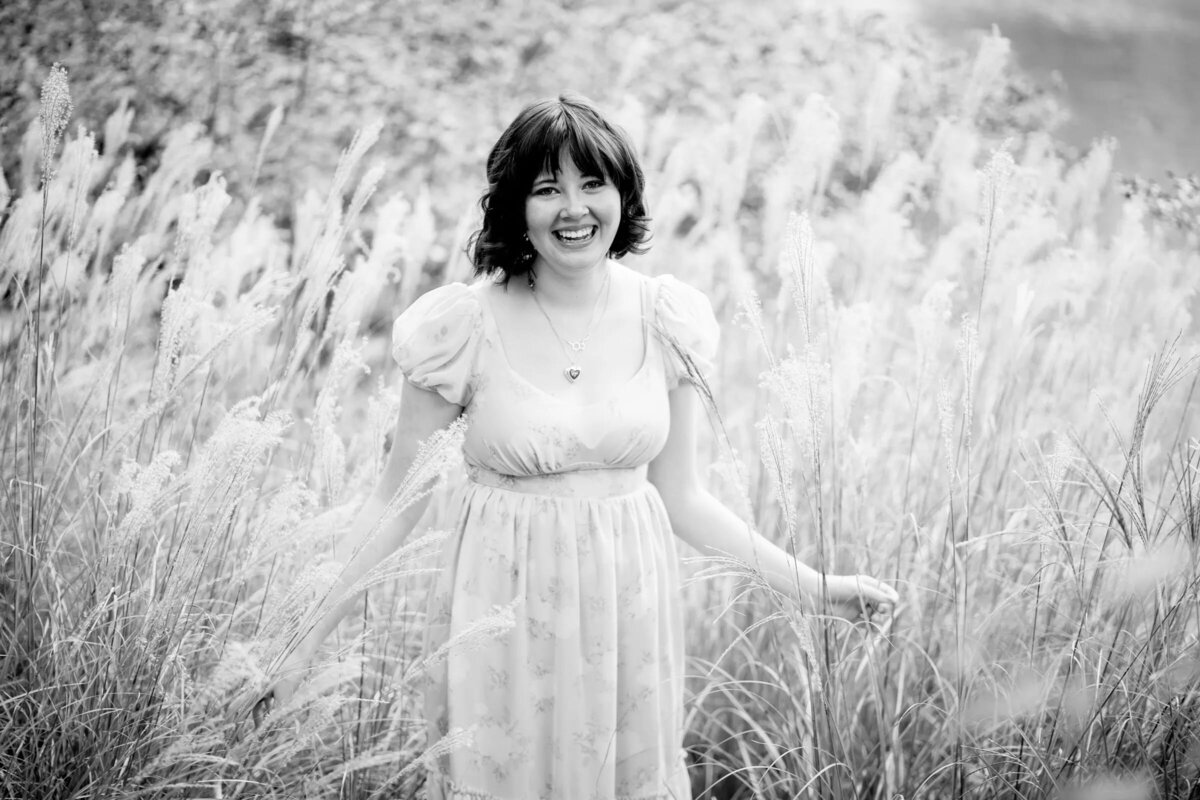 Black and white photo of a teenager walking through a field of tall grass.