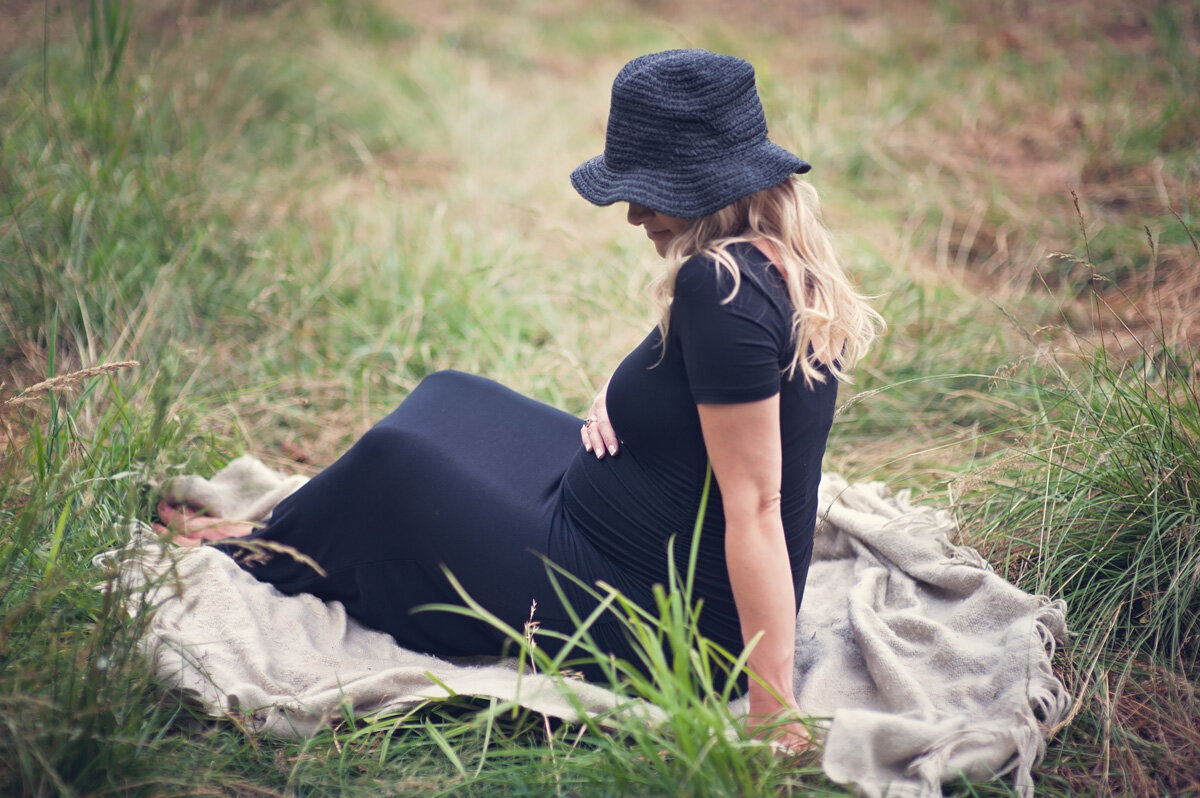 Maternity session with woman sitting on a blanket outside