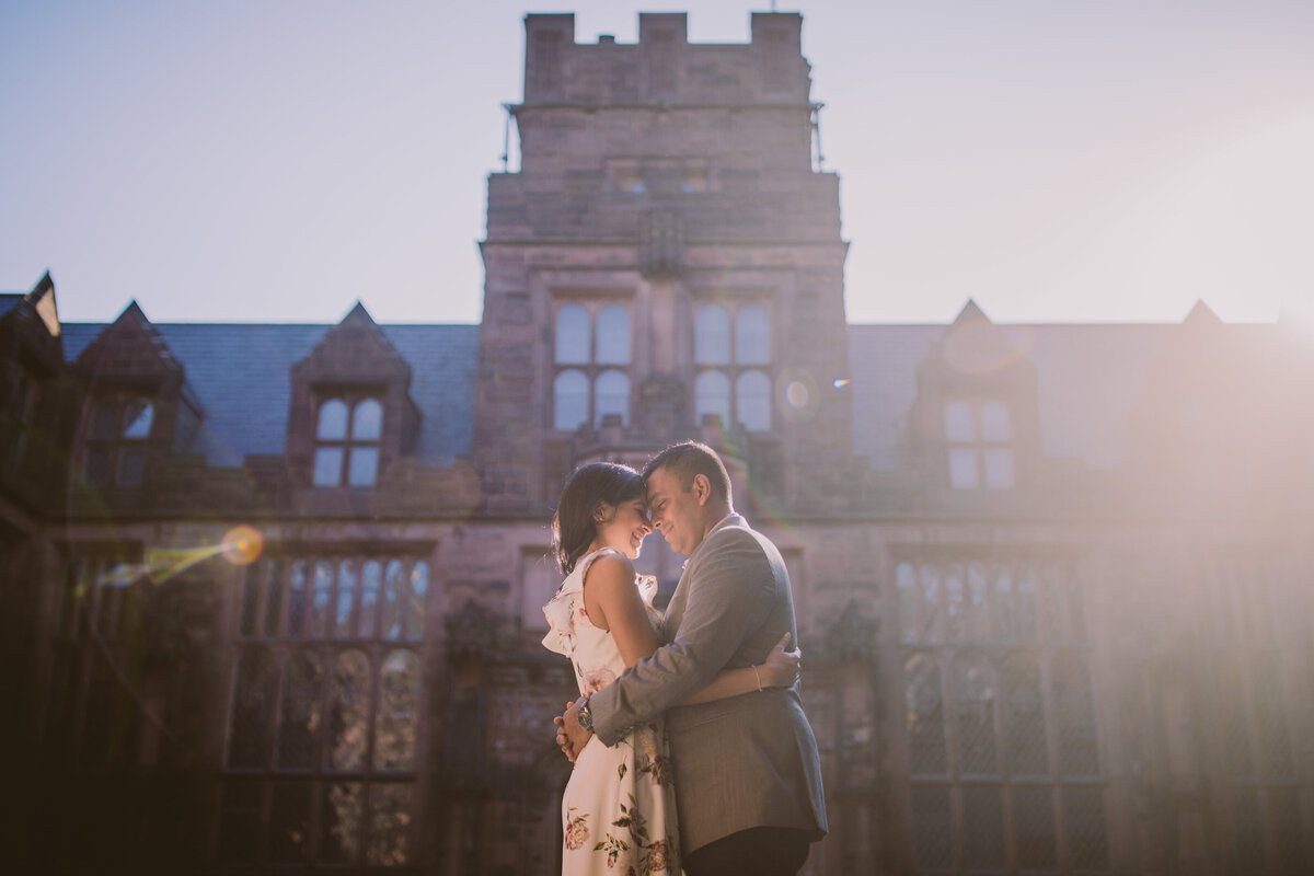 An engaged couple hugging with the east pyne hall in the background at princeton university in nj