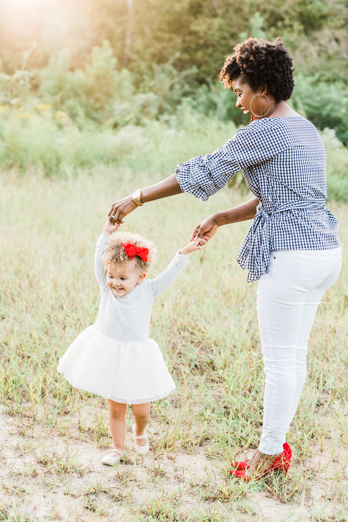 Mom twirls her daughter in a field during a family session in Raleigh NC. Photographed by Raleigh family photographer A.J. Dunlap Photography.