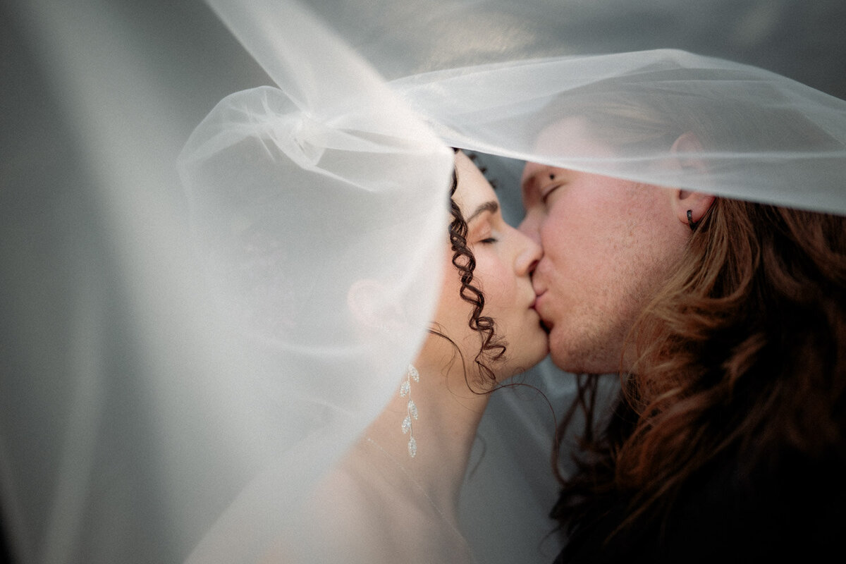Couple kiss underneath a veil