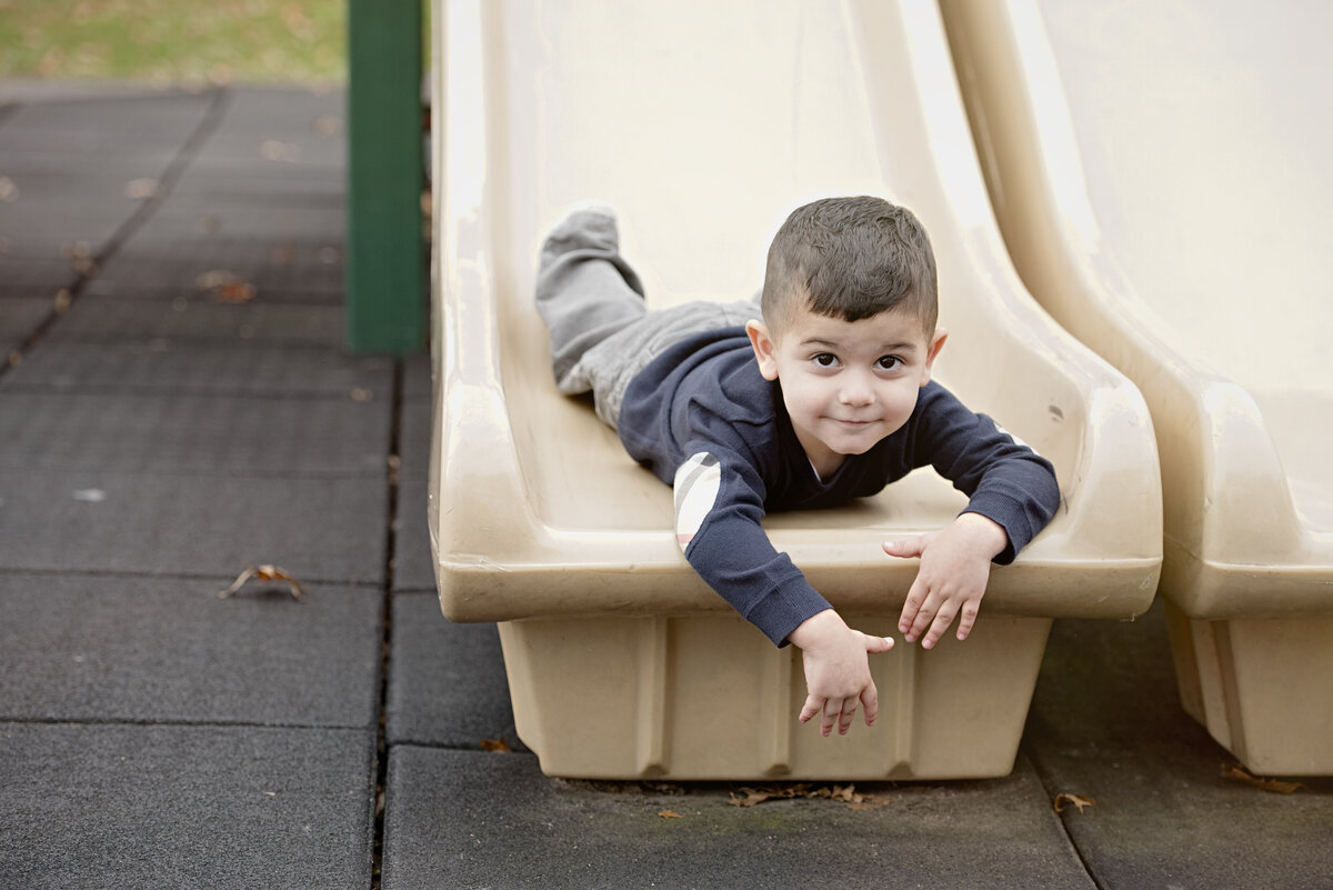 A child laying on their stomach at the bottom of a slide