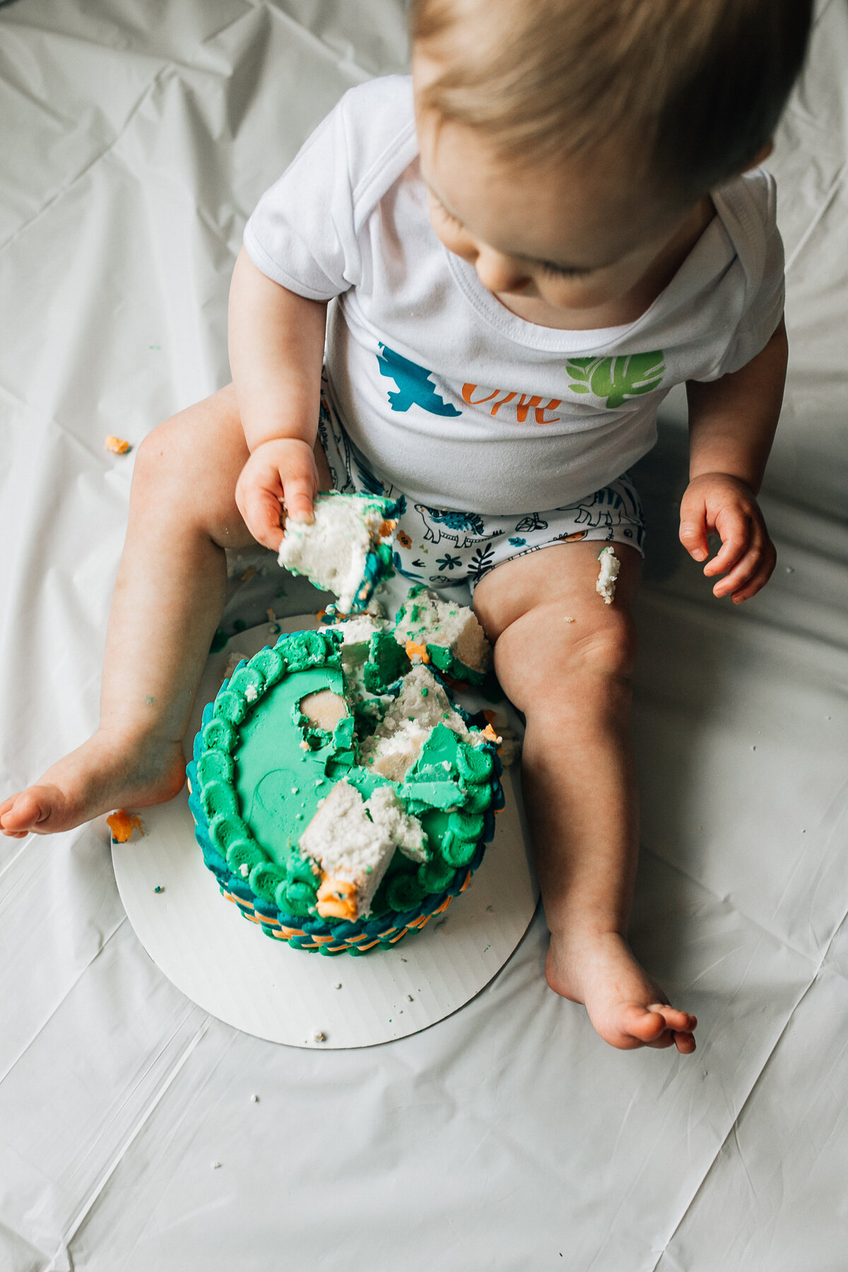Baby sits on the floor with cake.