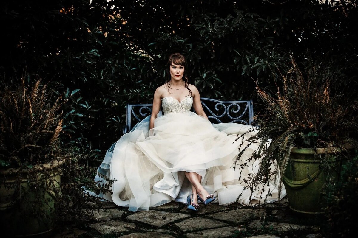 A bride sitting on an outdoor bench.