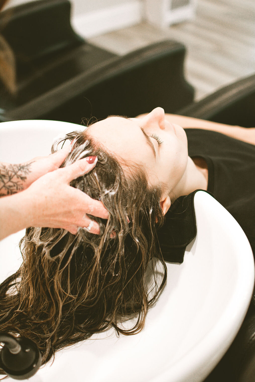 Hairstylist shampooing client's hair in salon shampoo sink