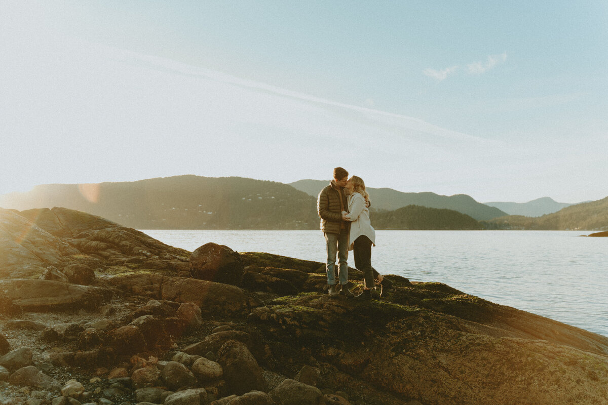 golden hour engagement photos of a couple kissing on a rocky shore