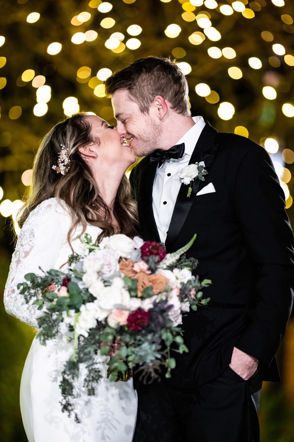Bride and groom kissing in front of lights at Southern Oaks