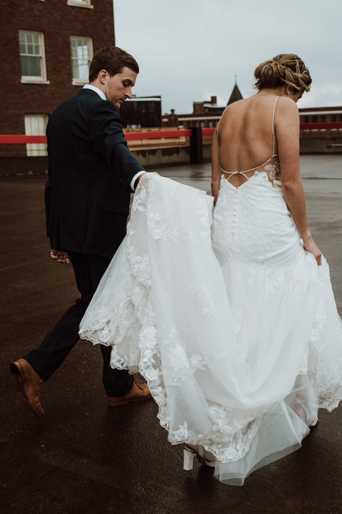 Groom walks with bride on rainy rooftop